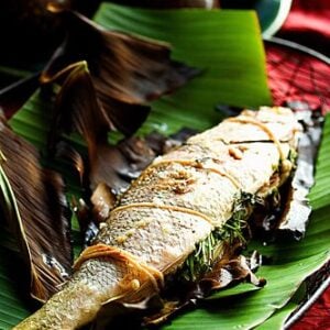 A grilled whole fish on a banana leaf