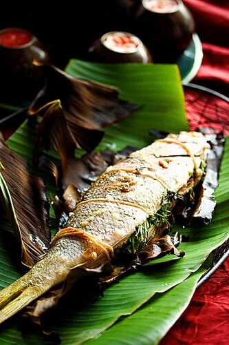 A grilled whole fish on a banana leaf