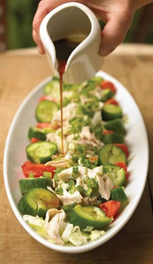 Sauce being poured over a chicken salad