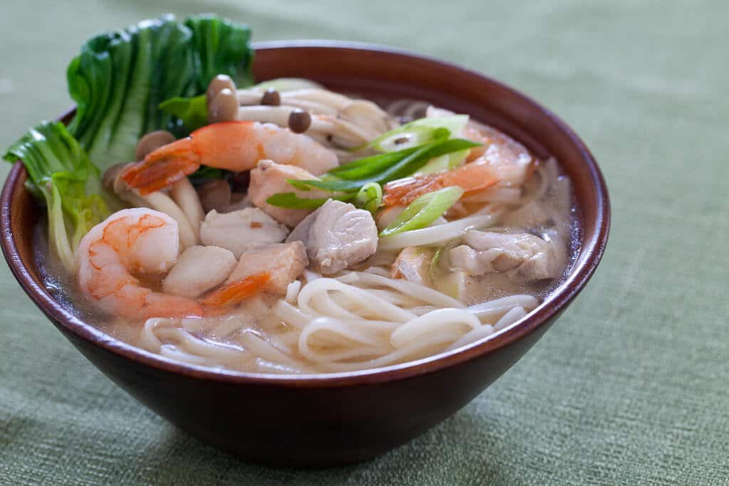 seafood noodle soup in brown bowl