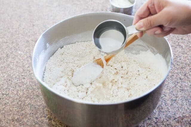 pouring more water in flour