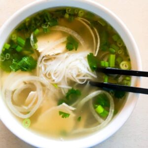 chicken pho in a white bowl with chopsticks