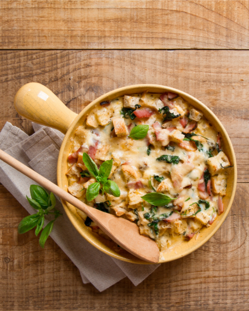 savory bread pudding with cheese and basil in a yellow pot 