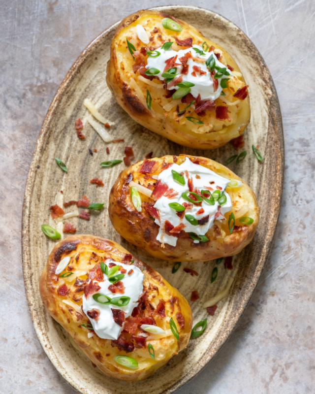 three baked potatoes on a grey plate.