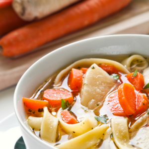 up close photo of chicken soup with carrots and noodles.
