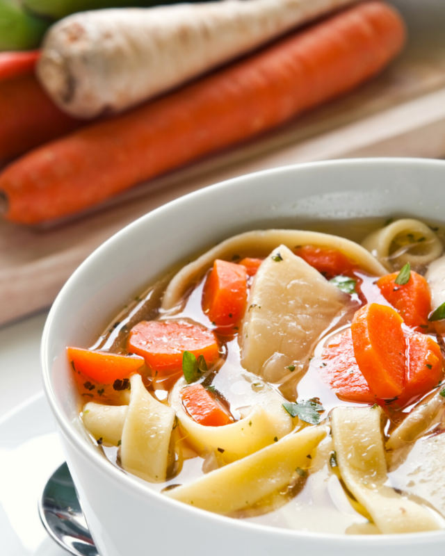 up close photo of chicken soup with carrots and noodles. 