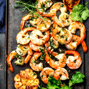 Cooked garlic shrimp on a sheet pan with fresh parsley.