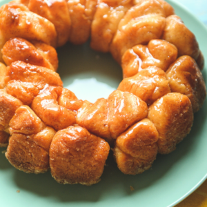 monkey bread with butter and cinnamon sugar over the top on a green plate.