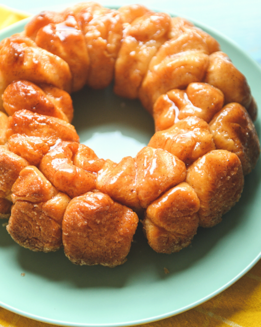 monkey bread with butter and cinnamon sugar over the top on a green plate.