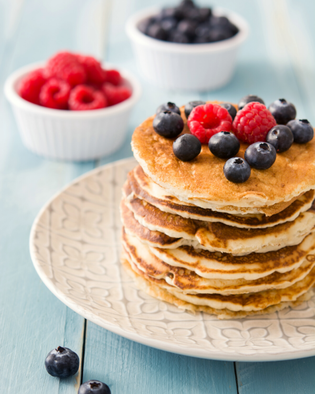 Pancakes stacked with fresh blueberries and raspbaerries.