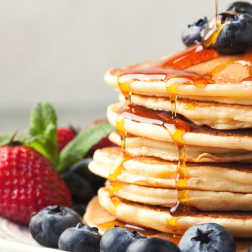 stacked pancakes dripping with maple syrup.