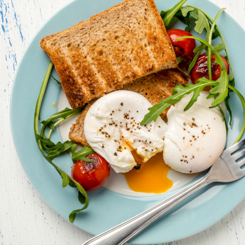 two poached eggs with a salad on a blue plate.