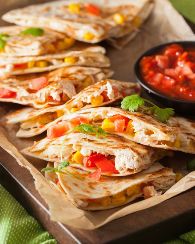 Tray of quesadillas on a small sheet pan with salsa. 
