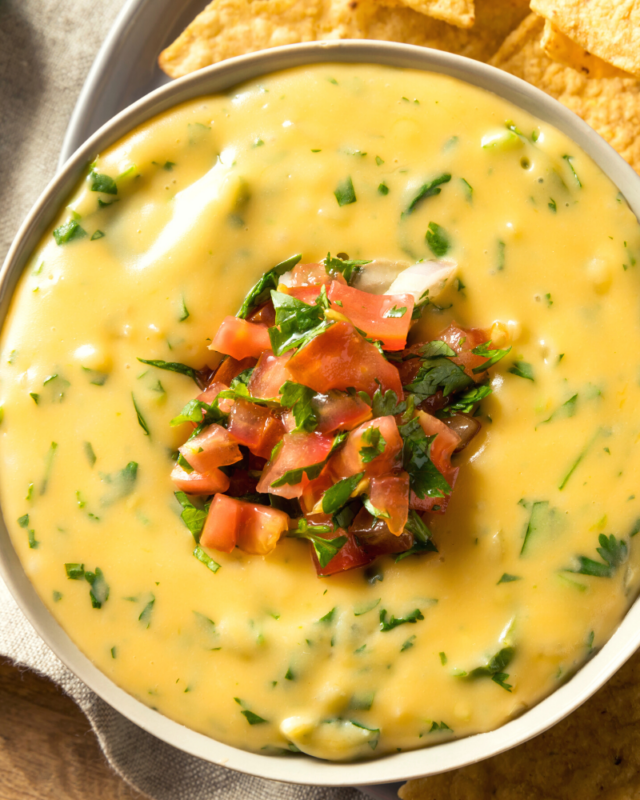 Up close shot of creamy queso in a white bowl. 