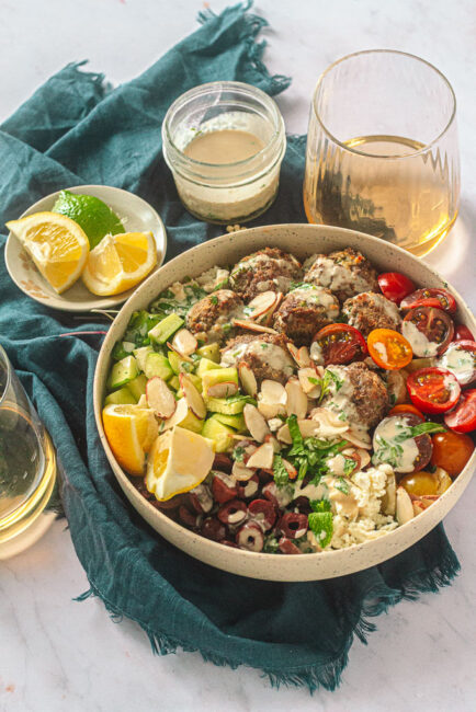 Greek Meatball Bowl With Lemon Tahini Drizzle with drinks and lemons