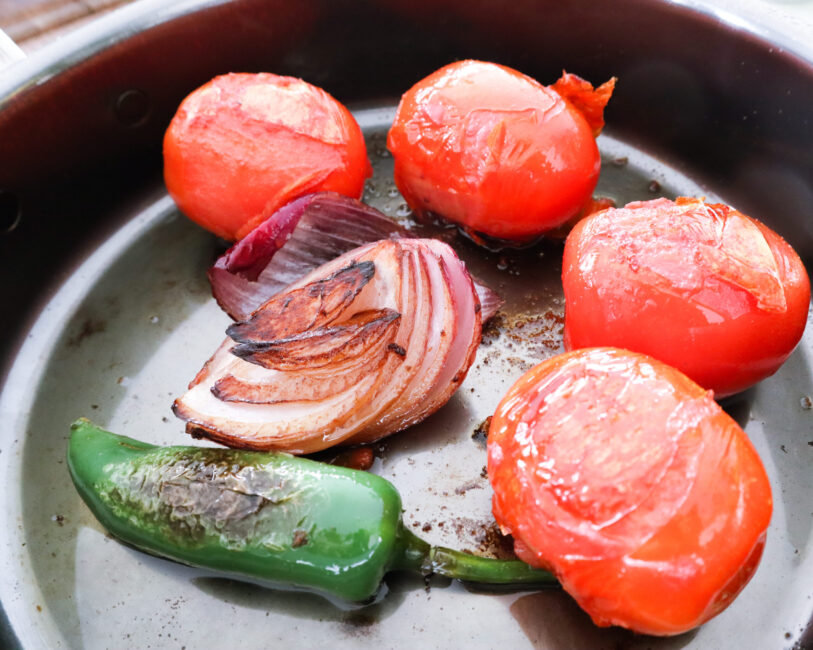 charred tomatoes, onions and jalapeno in a pan