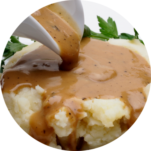 Brown gravy pouring on mashed potatoes.