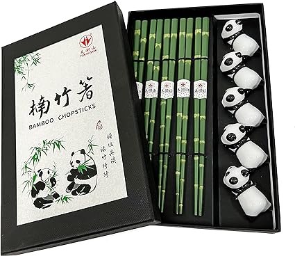 A boxed set of bamboo chopsticks with a green bamboo design, accompanied by white porcelain rests featuring cute panda faces, all presented in a sleek black box with traditional Chinese bamboo and panda illustrations on the cover.
