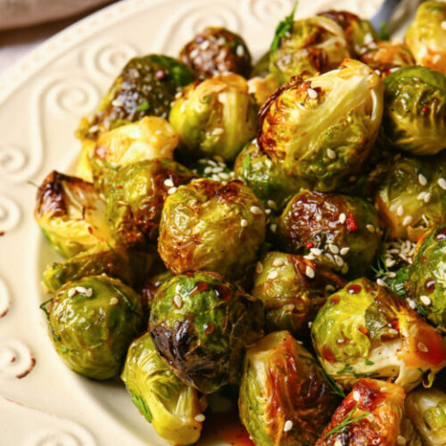 A beautiful green bed of cooked brussel sprouts topped with sesame seeds.