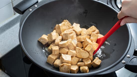 Cooking diced cubed dried tofu on gas stove.