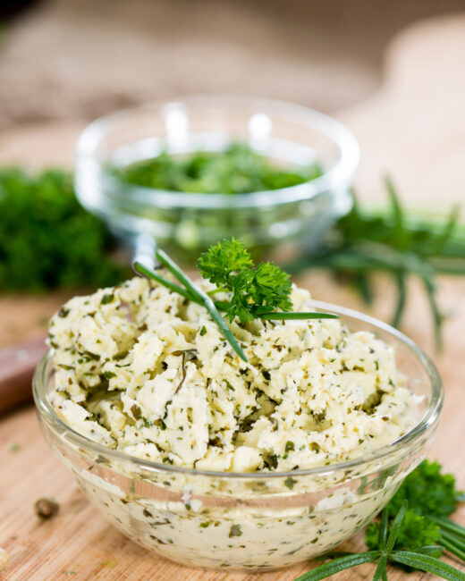 Herbed butter with fresh herbs in a glass bowl