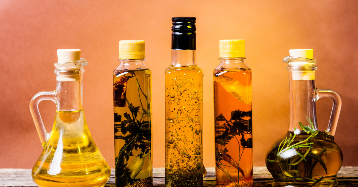 Flavored Oils with different flavors and herbs on orange background