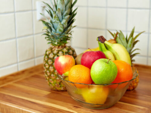 A bowl of assorted fruits sits on a kitchen counter