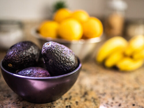 A bowl of avocados sits on a counter